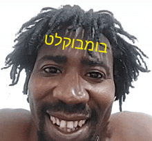 a man with dreadlocks and a beard is smiling with a yellow sticker on his head