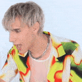 a man wearing a necklace and a colorful shirt with his mouth wide open