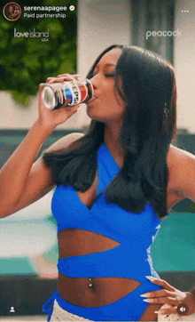 a woman in a blue top drinking a pepsi can