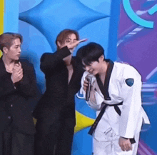 a man in a taekwondo uniform is talking into a microphone while standing next to another man .