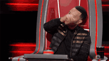 a man sitting in a chair with the word the voice on the bottom right