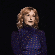 a woman with red hair is wearing a purple dress with stars on it and making a funny face .