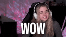 a woman wearing headphones is sitting in a chair with the word wow on the screen .