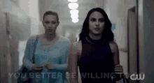 two women are walking down a hallway with the words `` you better be willing '' on the bottom .