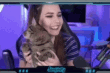 a woman is holding a cat while sitting in front of a microphone .