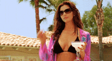 a woman in a bikini is holding a martini