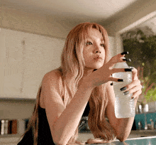 a woman in a black tank top is holding a white bottle of water
