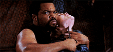 a man with a beard is holding a woman in his arms and cutting her neck with a pair of scissors