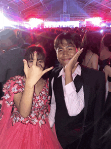 a boy and a girl are posing for a picture and the girl is wearing a pink dress with butterflies on it