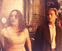 a man and a woman are standing next to each other in front of a clock