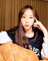a woman sitting on a couch with her finger on her forehead wearing a shirt that says ec