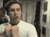 a man wearing a white shirt and a black tie looks at himself in a mirror