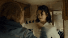two women are standing next to each other in a room and fighting .