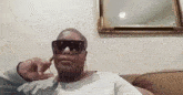 a woman wearing sunglasses and hoop earrings is sitting on a couch