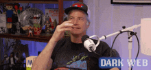 a man is sitting in front of a microphone with a sign that says dark web on the bottom