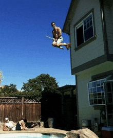 a man is flying through the air with a broom in front of a house