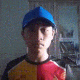 a young man wearing a blue hat and a black shirt looks at the camera
