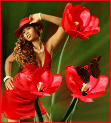 a woman in a red dress stands in front of red flowers