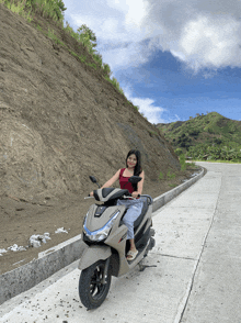 a woman sits on a honda scooter on a curvy road