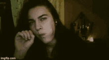 a woman with long hair is smoking a cigarette while looking at the camera .