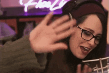 a woman wearing glasses and headphones is waving her hand at someone .