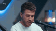 a man singing into a microphone with rtve written on the bottom