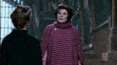 a woman in a purple sweater is standing next to another woman