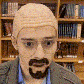 a man with glasses and a fake beard is standing in front of a bookshelf .