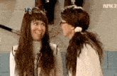 two women are talking in front of a wall that says nk2