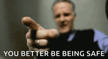a man is pointing at the camera with his finger and the words `` you better be being safe '' written below him .