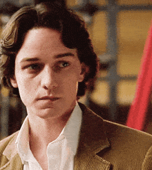 a close up of a man 's face wearing a brown jacket and white shirt