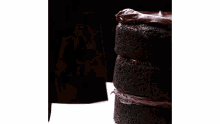 a close up of a chocolate cake with chocolate frosting being spread on it .