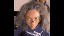 a close up of a girl wearing glasses and a blue hoodie .