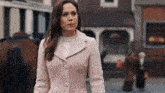 a woman wearing a pink coat is walking down the street