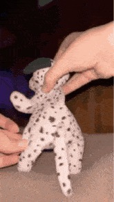 a person is holding a dalmatian stuffed animal with their finger .