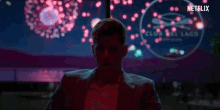 a man in a suit stands in front of a netflix sign