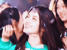 a girl in a green sweater is smiling and looking up at the sky