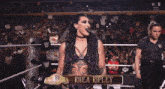 a woman in a wrestling ring holding a championship belt with the letter w on it