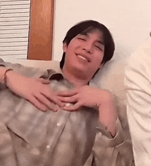 a man is sitting on a couch with his hands on his chest .