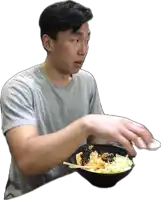 a man in a grey shirt is holding a bowl of food with chopsticks