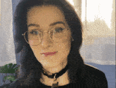 a woman wearing glasses and a black choker
