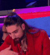 a man with long hair and a beard wearing a red shirt