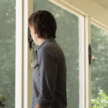 a man in a striped shirt is standing in front of a large window