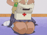 a person is kneeling down holding a box with a red cross on it