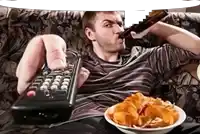 a man sits on a couch holding a remote control and a bowl of chips