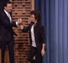 a man in a suit and tie is giving a woman a high five .