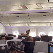 a man in a hat sits in a row of seats on a plane