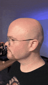 a man wearing glasses and a black shirt has a beard