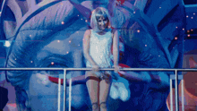 a woman in a wig is standing in front of a statue