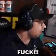 a man wearing headphones and a hat is holding a cell phone and saying `` fuck !!! '' .
